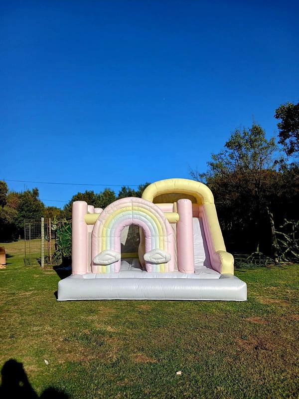 Pastel rainbow jumping castle hire with slide Johannesburg North - Bubble Bounce Bliss